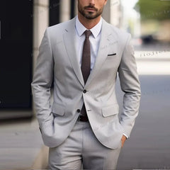 A man wears a light grey two-piece suit with a white shirt and a dark brown textured tie.