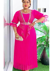 A woman wears a vibrant fuchsia pleated maxi dress with embellished lapels and a matching belt.