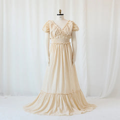 A cream-colored bohemian maternity maxi dress with a V-neck, ruffled sleeves, and a smocked waist.