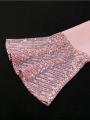 A close-up of a pink long sleeve with a ruffled cuff covered in shimmering sequins.