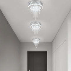 Three modern crystal raindrop ceiling chandeliers with polished chrome bases in a hallway.