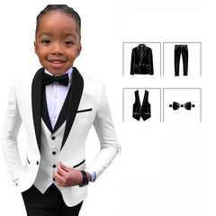 A young boy wears a white slim-fit tuxedo jacket with black lapels, a vest, pants, and a bowtie.