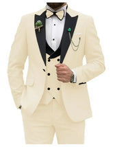 A cream-colored slim fit men's three-piece tuxedo suit with a black peak lapel and bow tie.