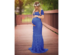 A pregnant woman wears a royal blue, short-sleeved, floor-length lace maternity gown.