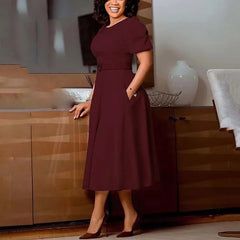 A woman wears a burgundy short-sleeved midi dress with a belted waist and pleated skirt.