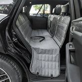 A grey quilted waterproof dog seat cover installed in the back seat of a car.