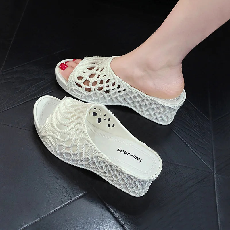 A pair of white wedge slippers featuring a hollow-out rope design and a thick platform sole.