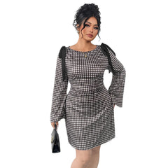 A woman wears a black and white gingham knee-length dress with long sleeves and shoulder bows.