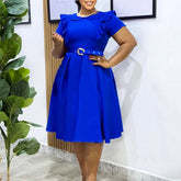A woman wears a royal blue, short-sleeved, A-line midi dress with a ruffled collar and a belt.