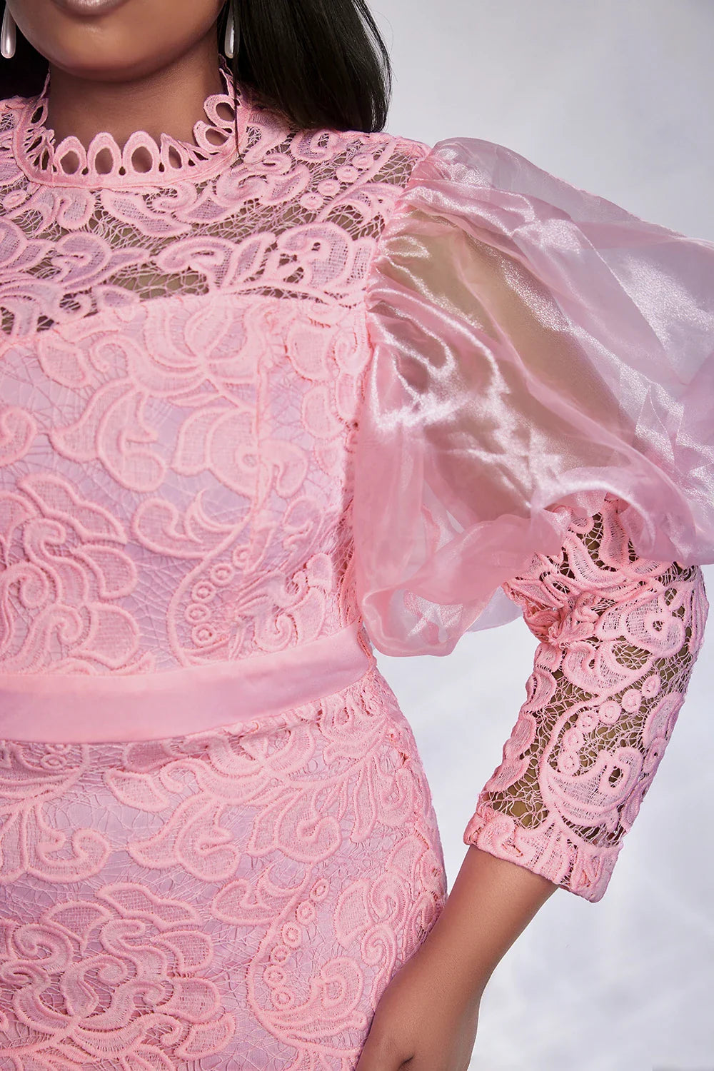 A pink lace midi dress featuring a high neckline and sheer puff sleeves.