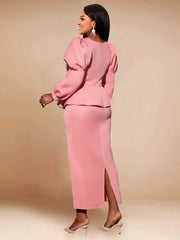 A woman wears a long-sleeved pink ankle-length dress with a peplum waist and puff sleeves.