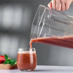A transparent 2L blender replacement jug pouring a strawberry smoothie into a glass.