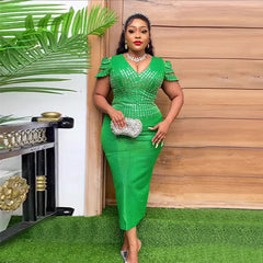 A woman wears a green bodycon midi dress with cold-shoulder sleeves and silver embellishments.