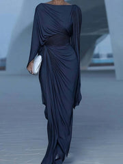 A woman wears a navy blue ankle-length evening dress with a draped bodice and long sleeves.