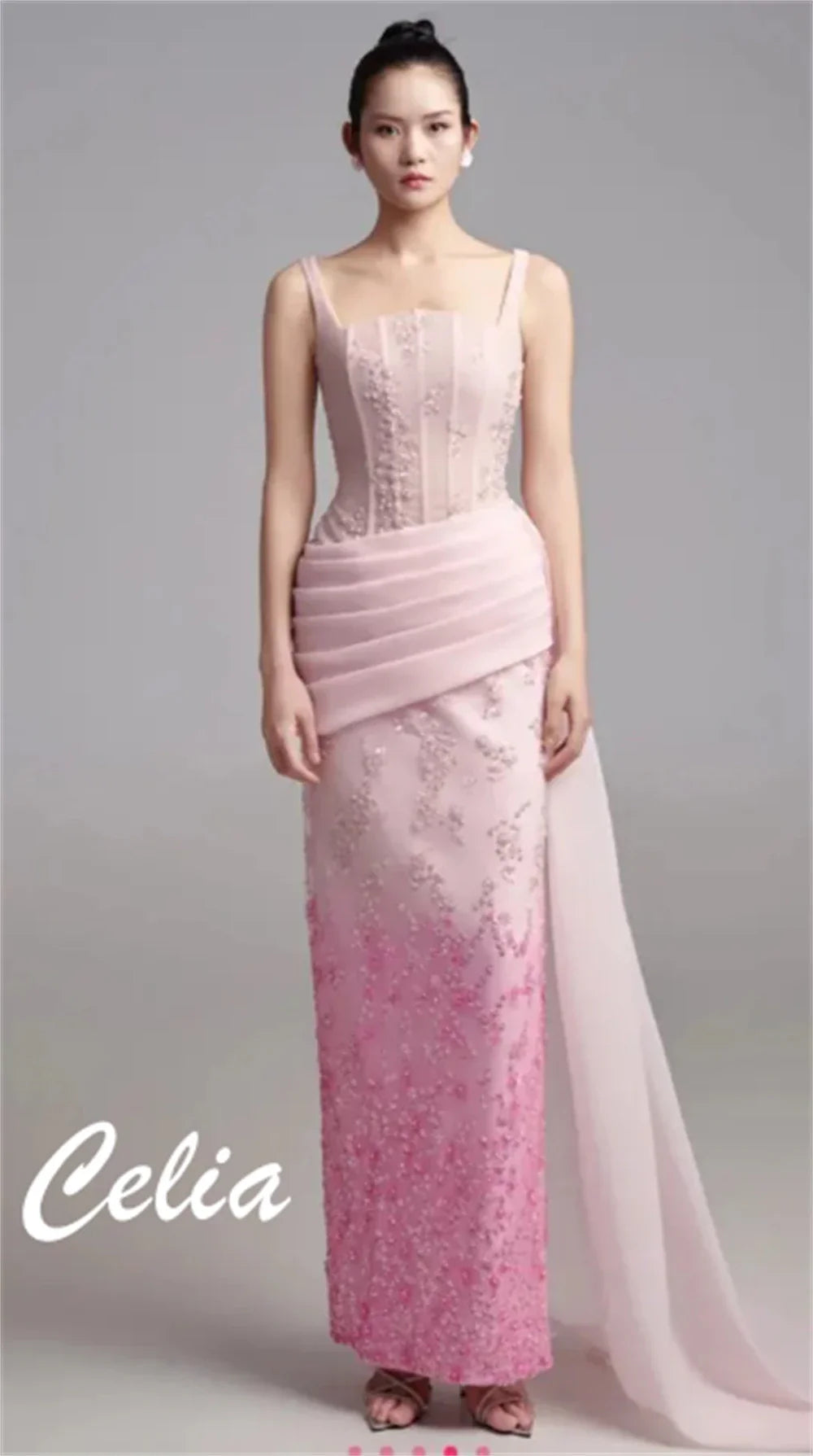 A floor-length pink evening gown with a pleated waist, floral embroidery, and a straight silhouette.