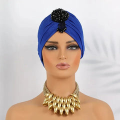 A royal blue pleated turban headscarf featuring a black beaded embellishment on the front.