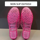 A pair of pink glittery jelly wedge sandals shown from the bottom to display the tread pattern.
