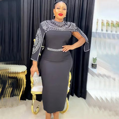 A woman wears a black midi dress with a beaded cape overlay and a matching waist belt.