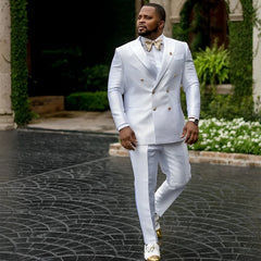A man wears a white double-breasted suit with a peaked collar and a gold bow tie.