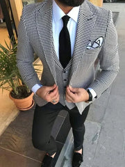 A man wearing a slim fit houndstooth three-piece suit with a white shirt and black tie.