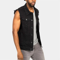 A man wears a black distressed denim vest with a lapel collar and raw-cut armholes.