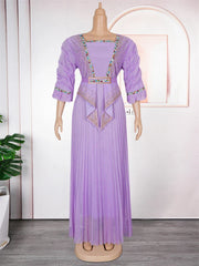 A lavender pleated maxi dress with embellished trim and a matching belt on a mannequin.