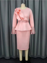 A pink midi dress with a peplum waist, ruffled shoulder detail, and sequined bell cuffs.