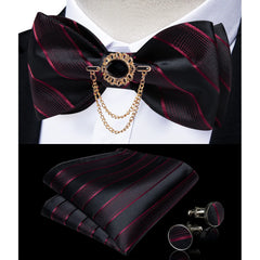 A black and burgundy striped bow tie set with a decorative brooch, pocket square, and cufflinks.