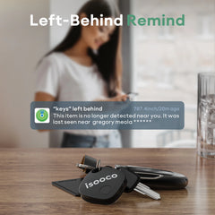 A black square smart key finder rests on a wooden table next to a set of keys.