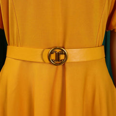 A mustard yellow pleated dress featuring a matching belt with a gold circular buckle.