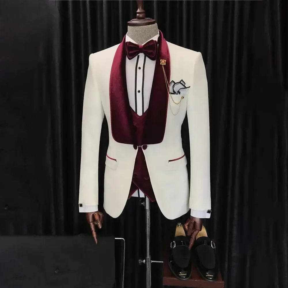 A white three-piece tuxedo featuring a burgundy velvet shawl lapel, vest, and matching bow tie.