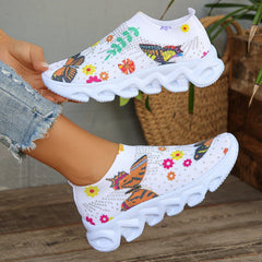 White slip-on sneakers featuring crystal butterfly and floral patterns on a mesh upper.