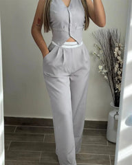A woman wears a light gray sleeveless buttoned vest and matching high-waisted straight-leg pants.