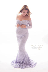 A pregnant woman wears a long-sleeved, off-the-shoulder lavender lace mermaid maternity gown.