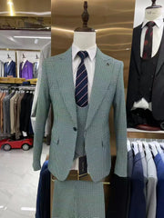 A slim-fit grey plaid three-piece suit with a white shirt and a striped tie on a mannequin.