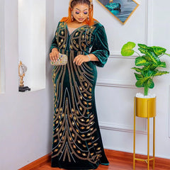 A woman wears a floor-length, dark green velvet evening dress adorned with gold diamond patterns.
