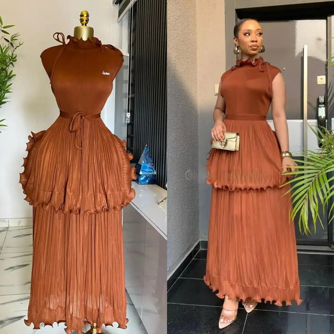 A sleeveless, rust-colored pleated midi dress with a ruffled peplum waist and a matching belt.