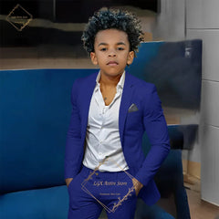 A boy wears a slim-fit blue single-breasted suit jacket and matching trousers with a white shirt.