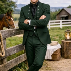 A man wears a dark green three-piece suit with a mandarin collar and black shirt.