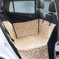 A tan dog car seat cover with a colorful puppy print installed in the back seat of a car.