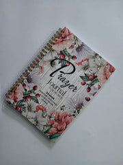 A spiral-bound prayer journal for women featuring a floral cover design on a white background.