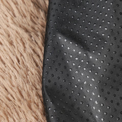 A close-up view of a black, non-slip fabric base with a textured dot pattern next to fluffy tan fur.