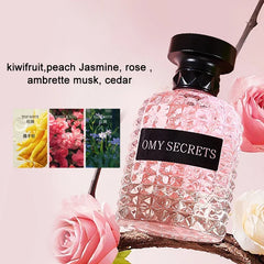A bottle of OMY SECRETS perfume with a textured glass design sits next to pink roses.