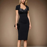 A woman wears a black short-sleeve knee-length sheath dress with a sweetheart neckline.