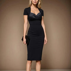 A woman wears a black short-sleeve knee-length sheath dress with a sweetheart neckline.