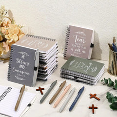 A collection of spiral-bound Christian journals and matching pens arranged on a desk.