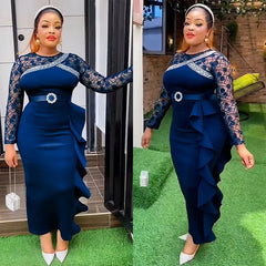 A woman wears a long-sleeved navy blue dress with lace detailing, a belted waist, and side ruffles.