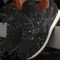 A pair of black lace-up sneakers covered in sparkling rhinestones with white platform soles.