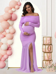 A pregnant woman wears a long-sleeved, off-shoulder lavender maternity gown with a side slit.