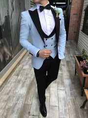 A man wearing a light blue three-piece suit with a black notch lapel, vest, and trousers.